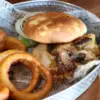Stage Stop Burger is topped with mushrooms and cheese and served with onion rings