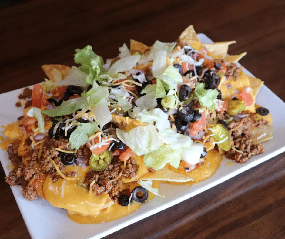 Stage Stop menu favorite appetizer is Cowboy Nachos on a large rectangular plate, loaded with fixings.