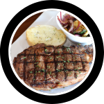 Ribeye steak on a plate with sautéed vegetables and garlic toast.